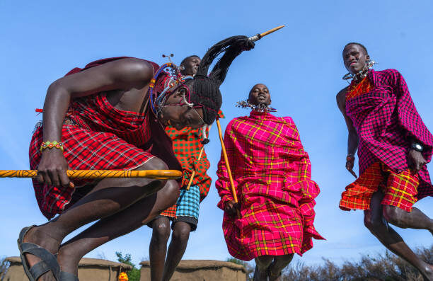Maasai Mara man in traditional colorful clothing showing traditional Maasai jumping dance at Maasai Mara tribe village famous Safari travel destination near Maasai Mara National Reserve Kenya